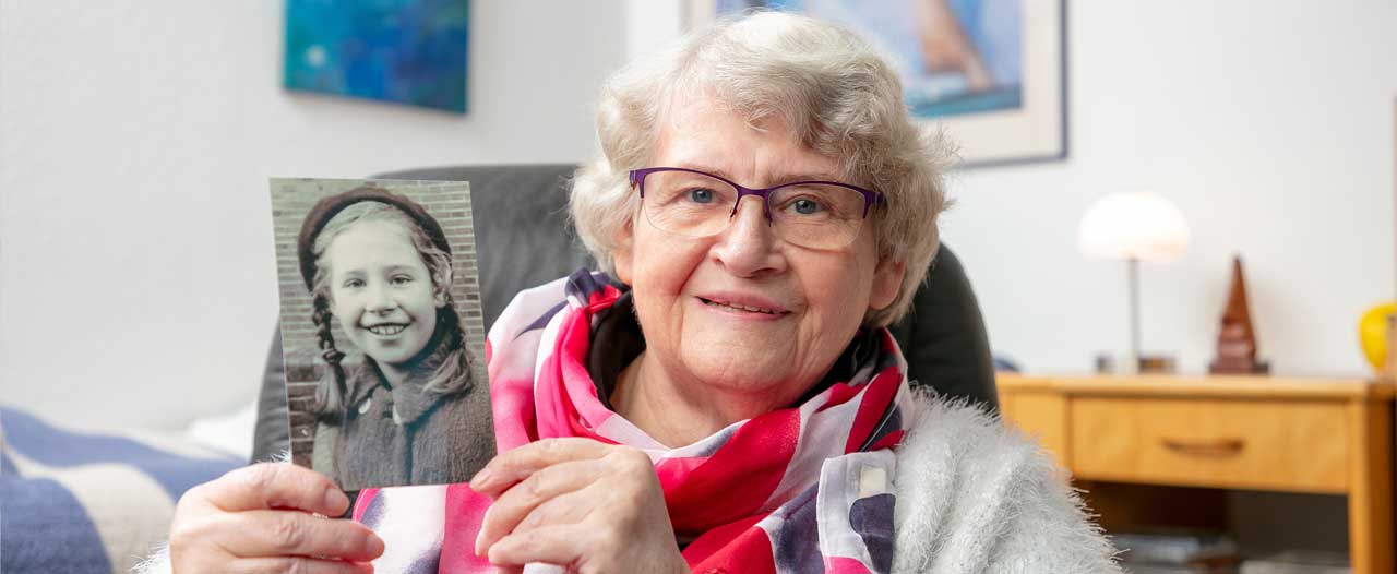 Ältere Dame zeigt ein Bild von sich als junges Mädchen